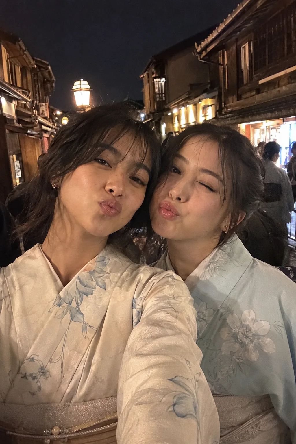 Mitsuki and a friend smiling in yukata on an evening street in Japan
